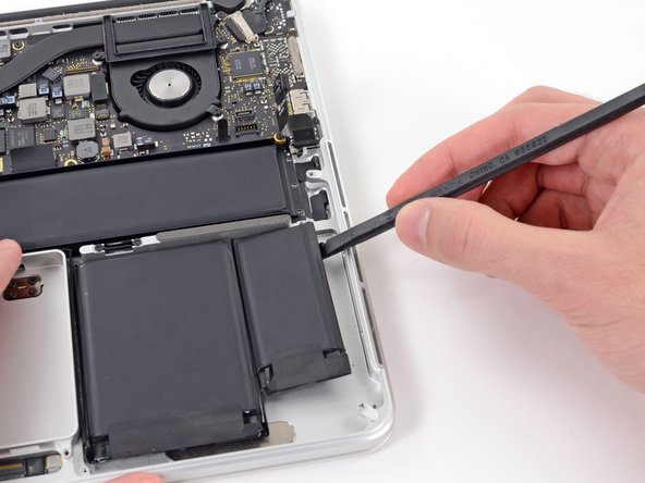 Image 2/2: Run the spudger up along the right side of the rightmost battery cell to release the adhesive.
