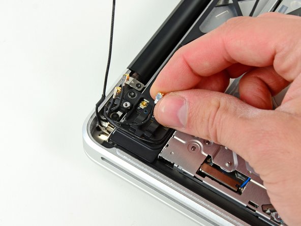 Image 2/3: De-route the camera cable from its channel in the AirPort/Bluetooth housing.