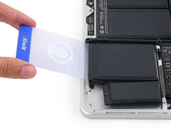 Image 1/3: Push the card about an inch between the battery cell and the upper case, and slowly pry the cell up to separate all of the adhesive.