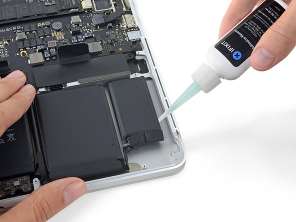 Apply a few drops of adhesive remover evenly under the edge of the rightmost battery cell.
