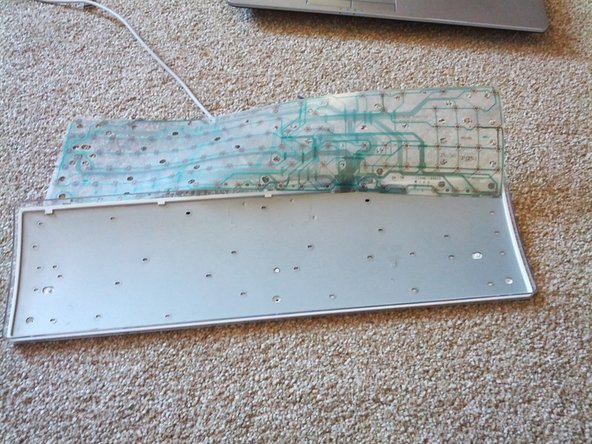 Image 2/3: Place the metal holder back into the keyboard retainer as in picture 2. Then gently fold the membrane back into place.
