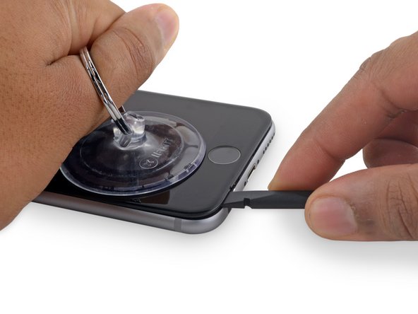 Place the flat edge of a spudger into the gap between the screen and rear case, directly above the headphone jack.