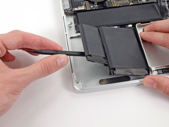 Image 3/3: Pry the larger leftmost battery cell up off the upper case.