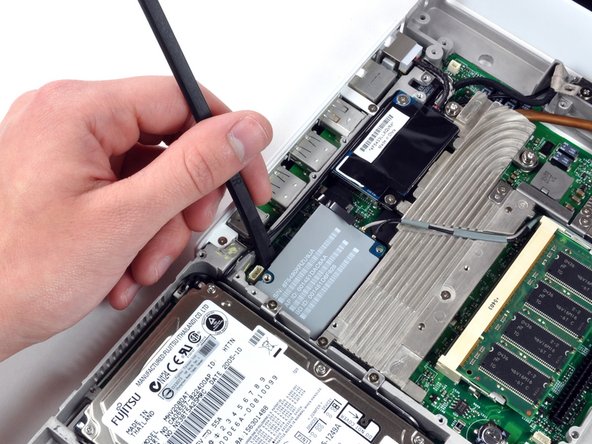 Image 1/1: Be sure to pry only between the metal framework and the AirPort card.