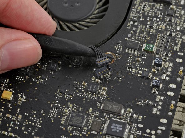 Image 2/3: It is useful to twist the spudger axially from beneath the fan cable wires to release the connector.