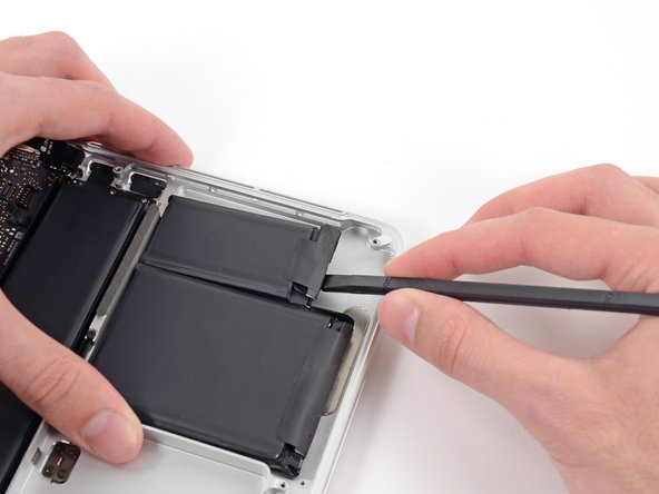 Image 3/3: Wedge the flat end of a spudger underneath the bottom portion of the rightmost battery cell.