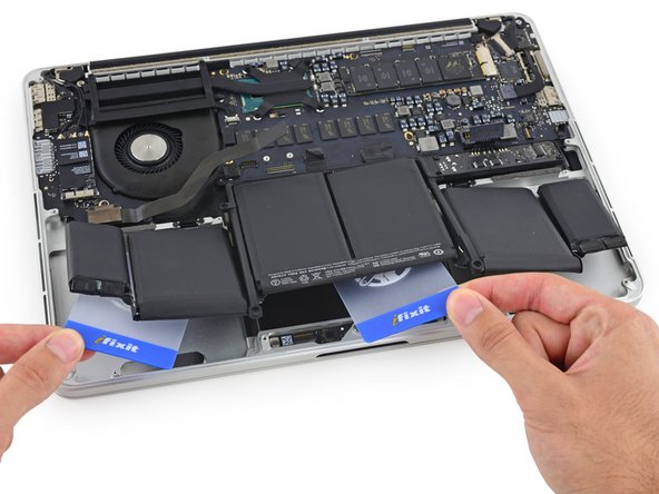 Image 2/3: Pry up on the two center cells to separate the last of the adhesive and remove the battery from the device.
