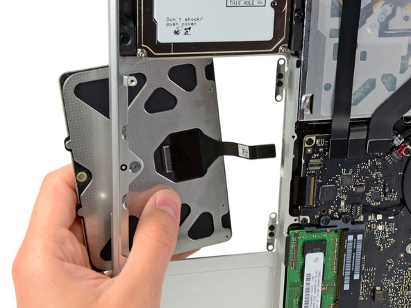 Image 3/3: Once the cable has been completely pulled through its slot in the upper case, pull the trackpad away from the outer edge of the upper case and remove it from the machine.