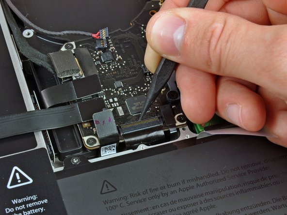 Image 2/3: Use your spudger to slide the keyboard ribbon cable out of its socket.