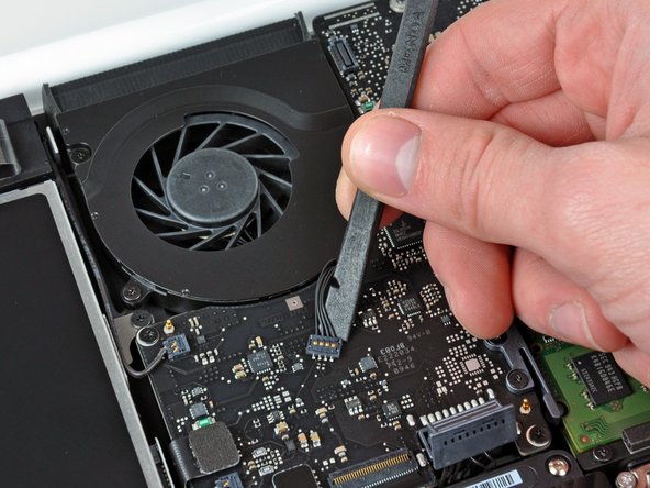 Image 1/3: It is useful to twist the spudger axially from beneath the fan cable wires to release the connector.