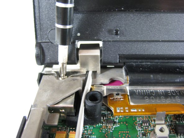 Image 1/1: Remove the single screw that secures the left hinge to top of the computer.
