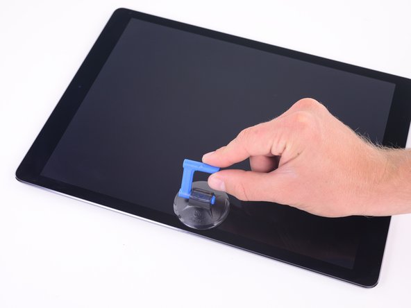 Attach a suction handle to the left edge of the iPad's display, equidistant from the top and bottom corners.