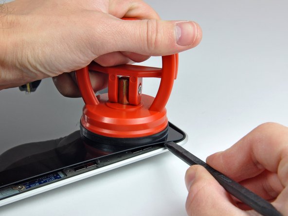 Image 2/2: Pull up on the suction cup and use the flat end of a spudger to carefully pry the glass display panel out of the display assembly.