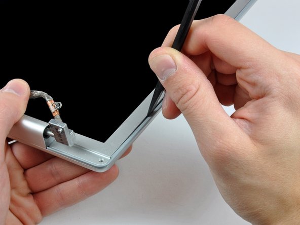 Image 1/3: With the spudger still inserted, rotate it away from the display to separate the front and rear bezels.