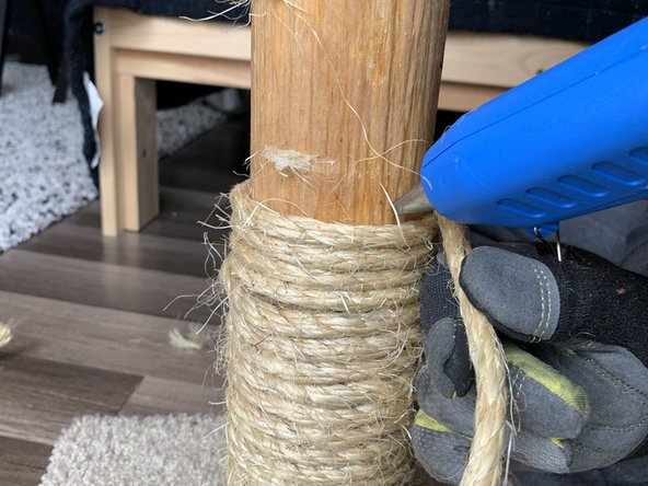 Every few layers or so, put a dab of hot glue on the post and continue wrapping the rope around the post.