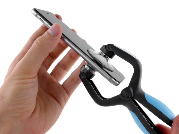 Image 2/2: Open the handles to close the jaws of the iSclack. Center the suction cups and press them firmly onto the top and bottom of the iPhone.