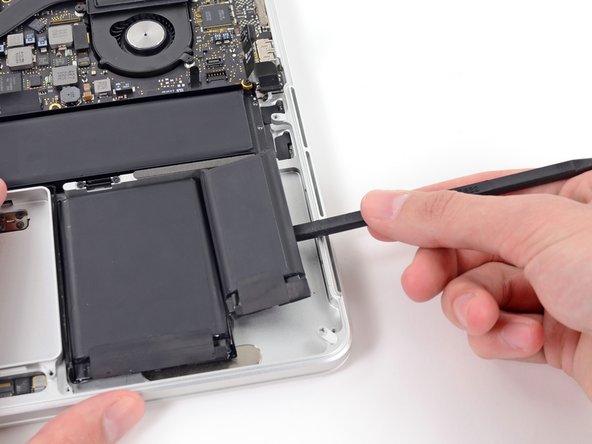 Image 2/2: Pry the spudger downwards to release the adhesive near the top portion of the rightmost battery cell.