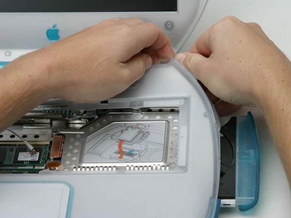 Image 1/1: Push out the rim of the lower case and pull up on the upper case, grasping it just to the left of the optical drive.