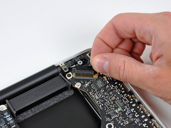 Image 2/3: Do not pull the cable upward, as the socket is very fragile. Pull the cable parallel to the face of the logic board toward the corner of the upper case.