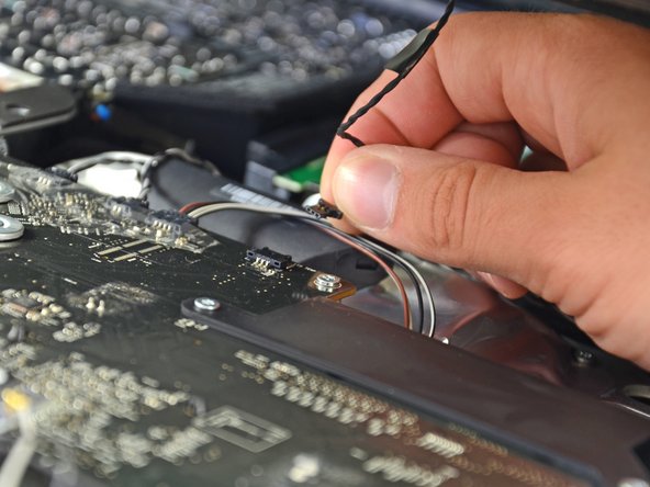 While holding the display panel up with one hand, locate and remove the display thermal sensor cable from its connector.