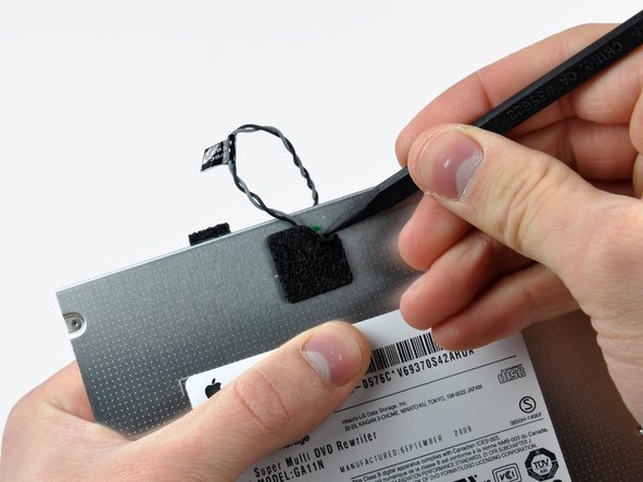 Image 1/2: Use the flat end of a spudger to carefully pry the thermal sensor up off the adhesive securing it to the optical drive.