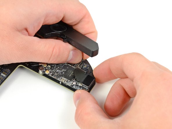 Image 1/2: Carefully lift the speaker wires upward to lift the speaker connector up and out of its socket on the logic board.