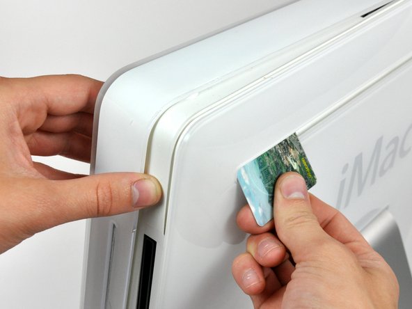 Image 2/3: Push the card toward the top of the iMac to release the front bezel latch.