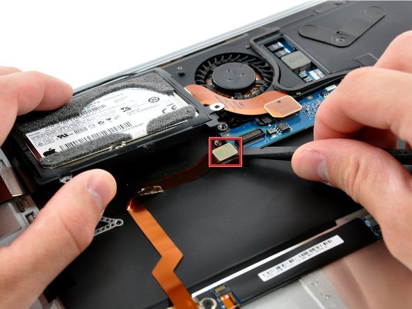 Image 1/2: Peel the audio cable off the adhesive securing it to the upper case.