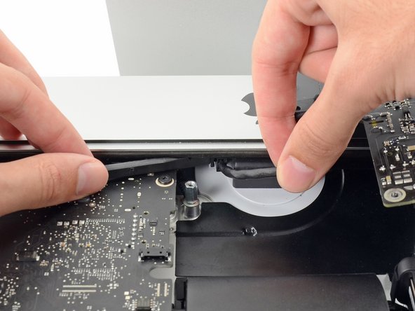 Image 1/3: Use the flat end of a spudger to push the clip on the side of the AC inlet cable connector inward.