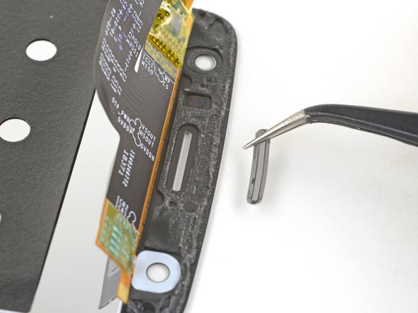 Use the flat edge of a spudger to push the grille from the front side of the screen to loosen it from its recess.