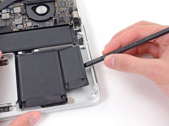 Image 1/2: Pry the spudger downwards to release the adhesive near the top portion of the rightmost battery cell.