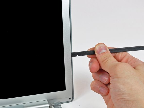 Image 2/3: With the spudger still inserted, rotate it away from the display to separate the front and rear bezels.