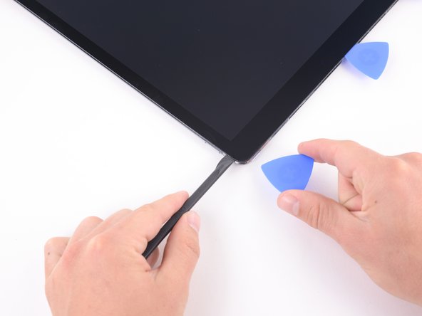 Bring the halberd spudger around the corner of the iPad and insert an opening pick in the upper right corner to prevent the adhesive from resettling.