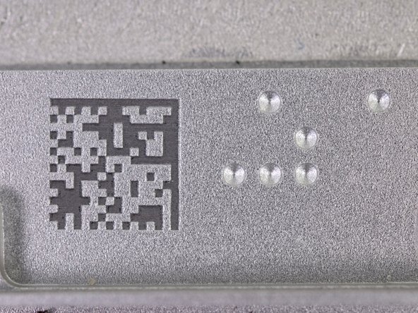 Image 2/2: The bottom edge of the case has two features that we found pretty neat: a ''laser engraved'' data matrix code and a nifty arrangement of round indentations.
