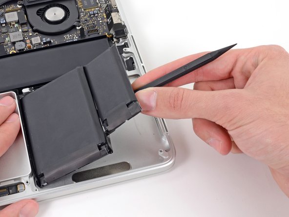 Image 3/3: Pry the larger right battery cell up off the upper case.