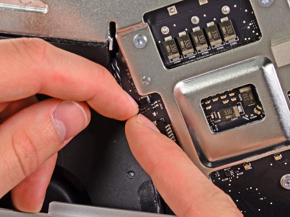 Image 2/3: Pull the power button connector toward the bottom left corner of the iMac to disconnect it from its socket on the logic board.