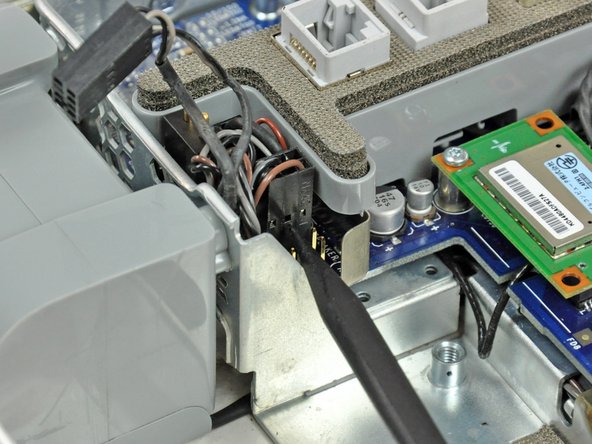 Image 1/2: With the spudger still inserted, lift the lower fan connector straight up off the logic board.