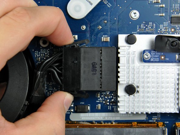 Image 1/2: After both locking arms pass their retaining tabs, it is helpful to push them toward the left edge of your iMac with one hand while pulling on the body of the connector with your other hand.