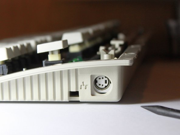 Image 1/3: Use a fingernail or a spudger to push the surface mount port upwards.