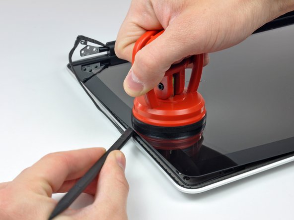 Image 2/2: Pull up on the glass panel while you use the flat end of a spudger to separate it from the rest of the display assembly.