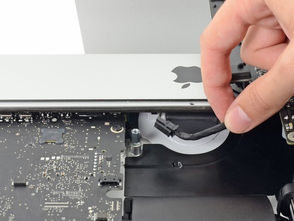 Image 3/3: While pressing on the release clip with the spudger, grasp the AC inlet cable, and pull the connector straight out of its socket.