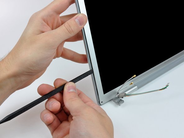 Image 2/3: With the spudger still inserted, rotate it away from the display to separate the front and rear bezels.