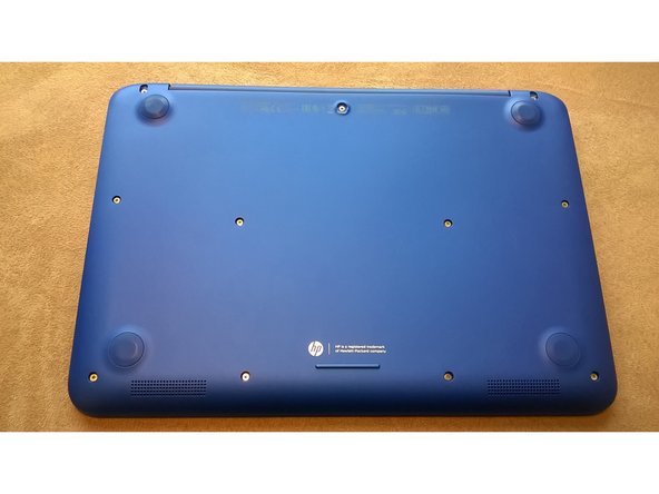 Flip your laptop over. There are four pads that you need to remove to access the screws. Remove the center pad first as shown in the picture.