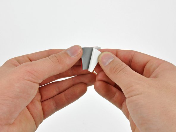 Image 2/3: Peel the backing off one side of the double-sided tape and place the pieces at the four corners of the hard drive.