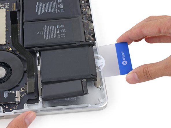 Insert the plastic card between the second left-most battery cell and the upper case to cut the adhesive joining the two, and pry the cell up from the case.
