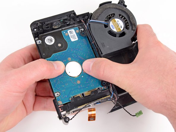 Image 1/2: Lift the hard drive from the edge opposite the fan and remove it from the internal frame.