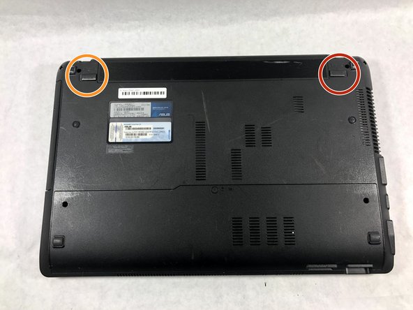 Turn the laptop upside down so that the underside is facing up and locate the two switches that are on each side of the battery.