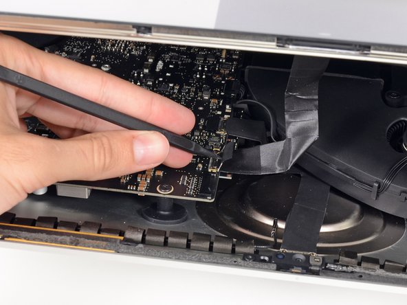 Image 1/3: Carefully pull the display data cable from its socket on the logic board.