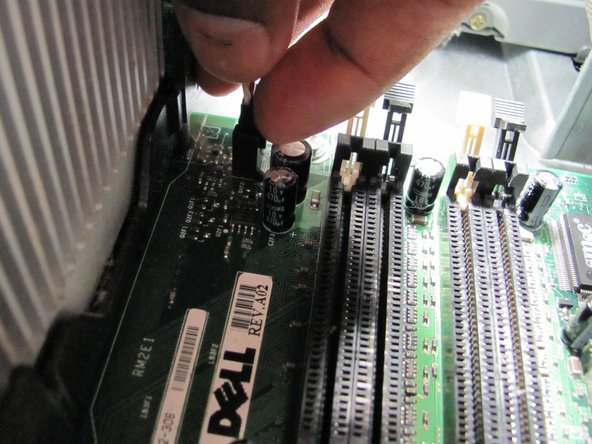 Image 1/1: Follow the power cable to the motherboard connection and remove it by pressing down on the clip.