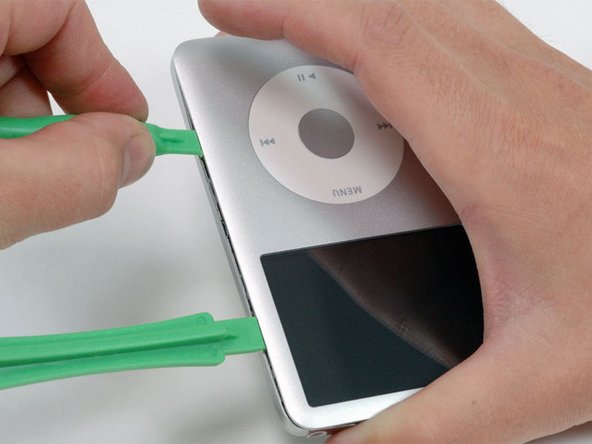 Remove the opening tool from the top corner and insert it into the seam between the front and back of the iPod, leaving at least 1.5 inches of space between the two tools (as done on the other side).